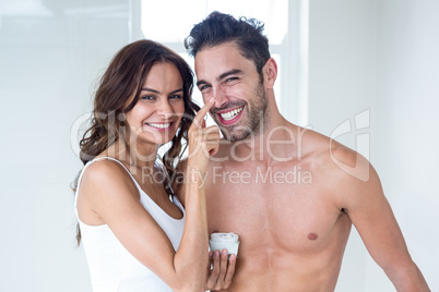 Wife applying cream on husband face at home