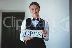 Smiling waitress holding open sign