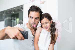 Father and daughter making faces while taking self portrait