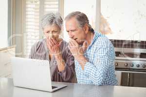 Shocked senior couple looking at laptop