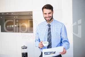 Portrait of businessman reading newspaper while drinking coffee