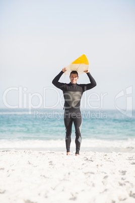 Happy man holding surfboard over head