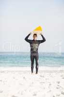 Happy man holding surfboard over head