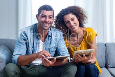 Portrait young couple sitting on sofa and using digital tablet