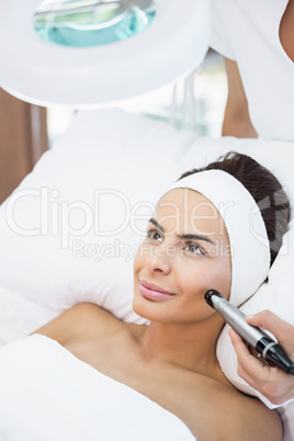 Close-up of thoughtful young woman receiving facial massage