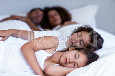 Family sleeping on bed