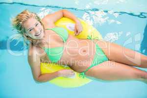 Beautiful woman in green bikini relaxing on inflatable tube in s