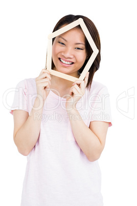 Young woman holding house shaped popsicle sticks on face