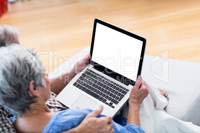 Senior couple using a digital tablet on sofa