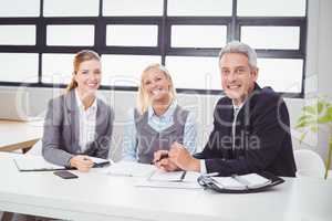 Happy business people sitting with client at desk