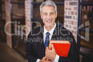 Male lawyer standing with red book at office