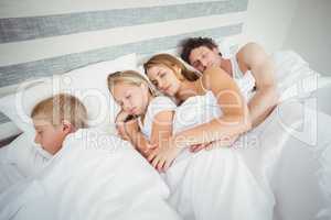 High angle view of family resting on bed