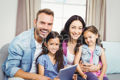 Family smiling while sitting on sofa at home