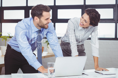 Business people smiling while leaning by laptop