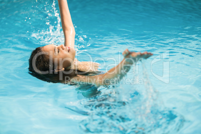 Beautiful woman splashing water in swimming pool