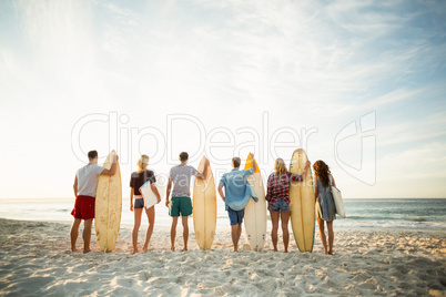 Friends holding surfboard on the beach