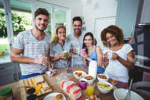 Portrait of cheerful friends holding drinks