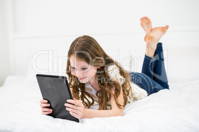 Girl using digital tablet on bed
