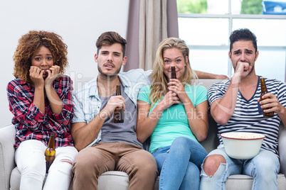 Nervous multi-ethnic friends watching TV at home