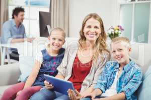 Happy mother sitting with children on sofa