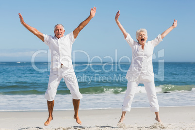 Senior couple jumping at the beach