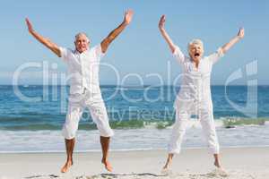 Senior couple jumping at the beach