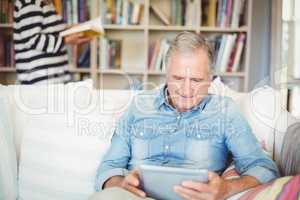 Senior man using tablet while sitting on sofa