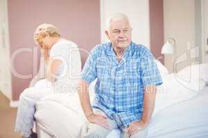 Tensed senior couple sitting on bed