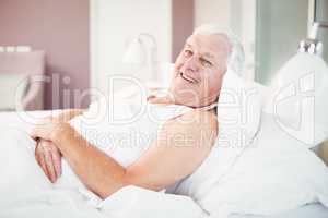 Portrait of cheerful senior man relaxing on bed