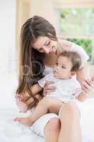 Young woman sitting with baby on bed