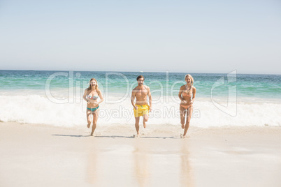 Happy young friends running on the beach