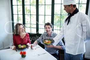 Chef showing the meal plate to couple
