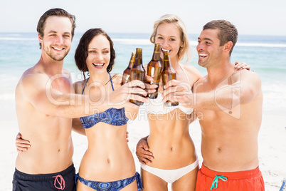 Happy friends toasting beer bottles on the beach