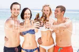 Happy friends toasting beer bottles on the beach