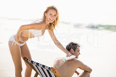 Woman making a heart symbol on mans back while applying a sunscr