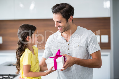 Smiling daughter giving gift box to father