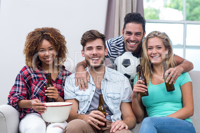 Multi-ethnic friends enjoying beer while watching soccer match