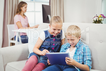 Children using digital tablet while mother in background