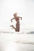 Excited woman in bikini jumping on the beach