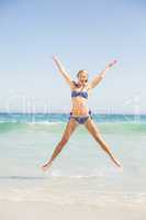 Carefree woman in bikini jumping on the beach
