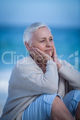 Thoughtful mature woman sitting on the sand