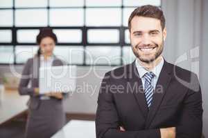 Confident young businessman while colleague in background