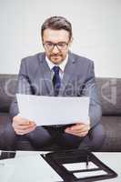 Businessman reading document while sitting on sofa