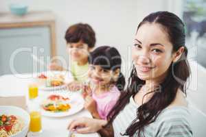 Portrait of smiling mother with children at dining table