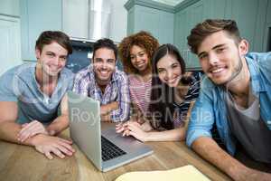 Portrait of young friends smiling while using laptop