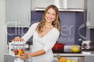 Portrait of smiling young woman using juicer