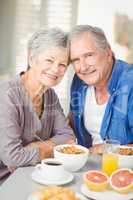 Portrait of smiling senior couple at table with breakfast
