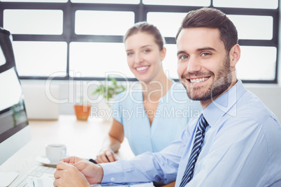 Confident business people sitting at computer desk