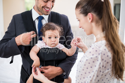 Smiling father carrying baby with mother