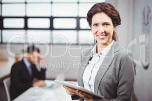 Businesswoman using tablet computer while colleague in backgroun